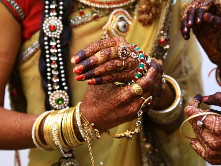 A bride's hands with intricate mehndi, gold bangles and rings